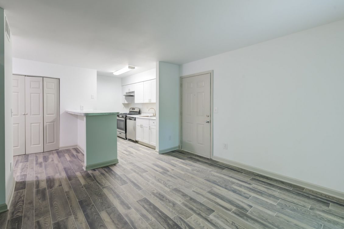 Open-concept living and dining area with wood-style flooring, breakfast bar, and natural light at Madison Laurel Oaks apartments in North Raleigh, NC